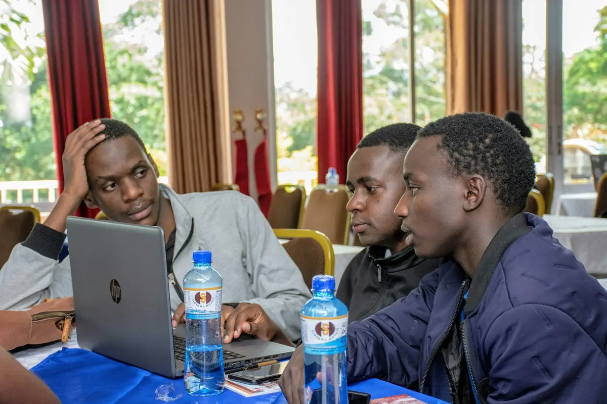 Trois hommes travaillent sur des ordinateurs portables autour d'une table